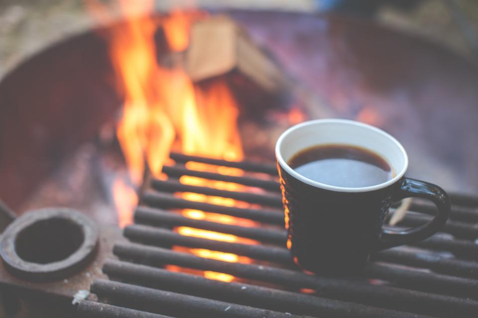 Sort kaffekop ved et bål som symbol på koffein før en løbetur