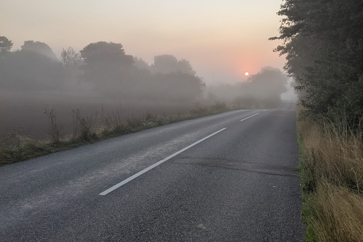 Tom landevej i morgendis ved solopgang, velegnet som billede til morgenløb